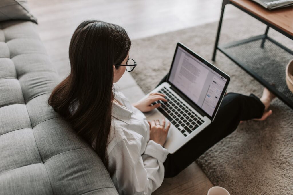 Studierende arbeitet an einer wissenschaftlichen Arbeit am Laptop auf dem Sofa Sprachliche Fehler vermeiden Häufige Stolperfallen beim Schreiben wissenschaftlicher Arbeiten